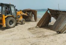 Truck demolishing straw umbrellas illegally erected to use the beach.