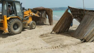 Truck demolishing straw umbrellas illegally erected to use the beach.