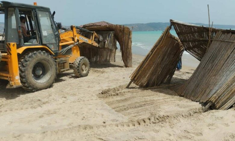 Truck demolishing straw umbrellas illegally erected to use the beach.