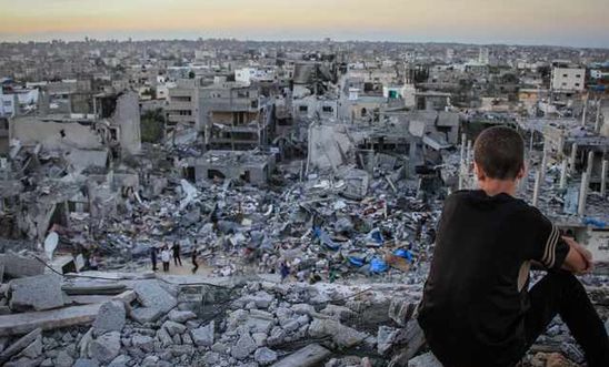 A young child sitting on the rubble of a destroyed house in Gaza. Photo by Ibrahim Khader/ Pacific Press/ Light Rocket via Amnesty International via Getty Images.